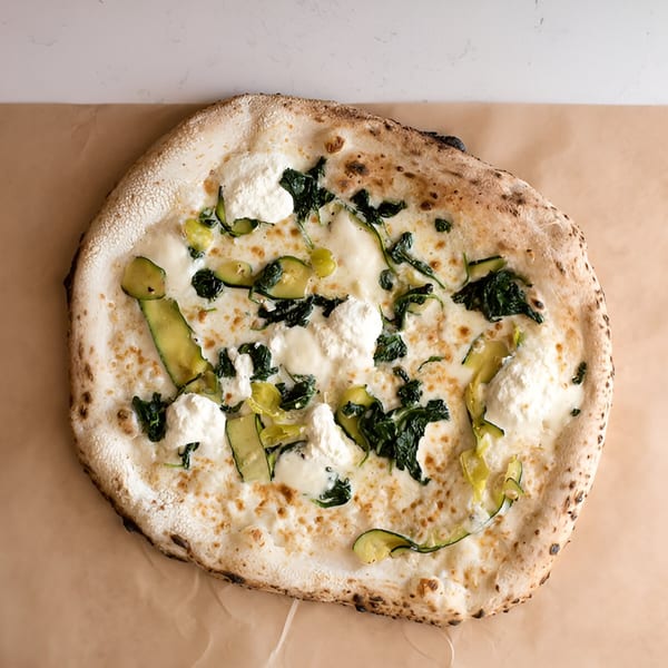 Napoli 1 Pizza's white pizza with ricotta, spinach, and zucchini on a light brown surface.