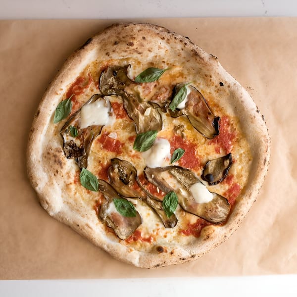 Napoli 1 Pizza's eggplant pizza with tomato sauce, mozzarella, and fresh basil on parchment paper.
